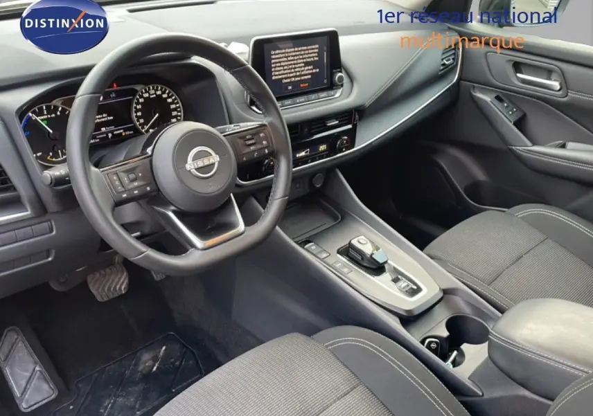 Vue intérieure côté conducteur du Nissan Qashqai 1.5 E-POWER 2023, avec volant cuir noir et console centrale moderne.
