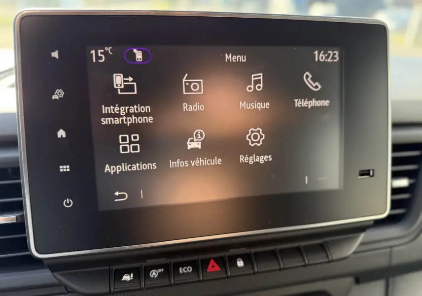 Écran tactile central du tableau de bord du Renault Trafic noir, affichant le menu multimédia avec smartphone et radio.