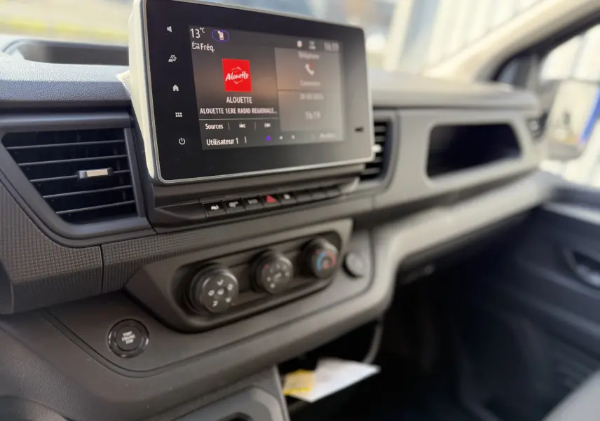 Vue rapprochée du tableau de bord du Renault Trafic cabine approfondie noir, avec écran tactile et commandes climatisation.