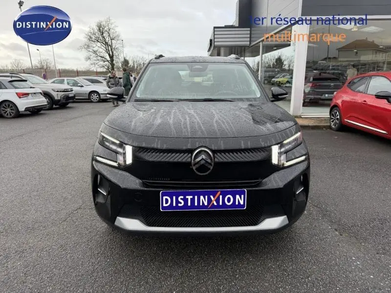 Vue avant d'une Citroën C3 1.2 Turbo 100ch PLUS noire Perla Nera avec phares allumés sur parking de concession.