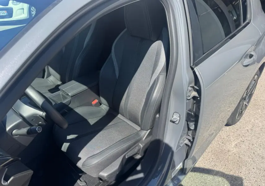 Vue côté conducteur de la Peugeot 308 Hybrid gris 2025, avec siège avant réglable et accoudoir central visible.