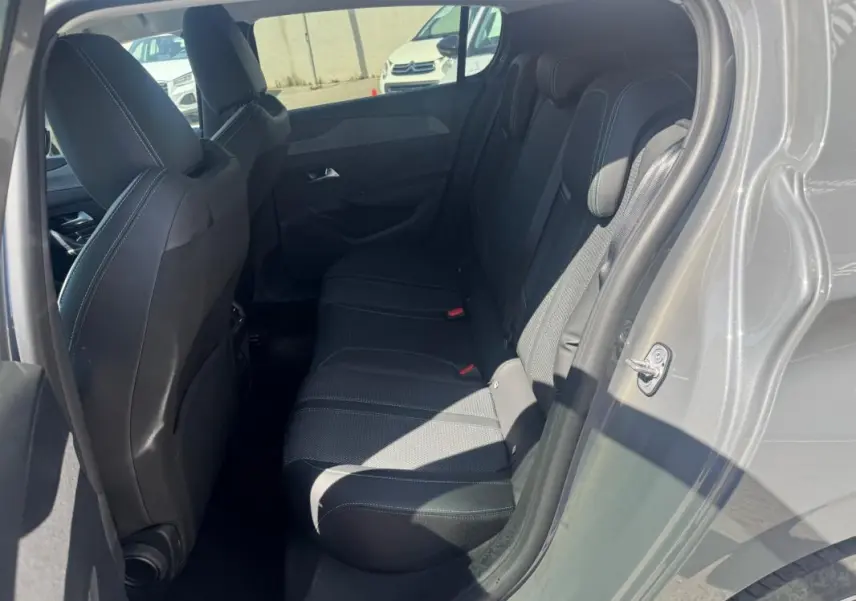 Vue intérieure côté droit sur les sièges arrière noirs d'une Peugeot 308 Hybrid gris 2025, avec porte ouverte.