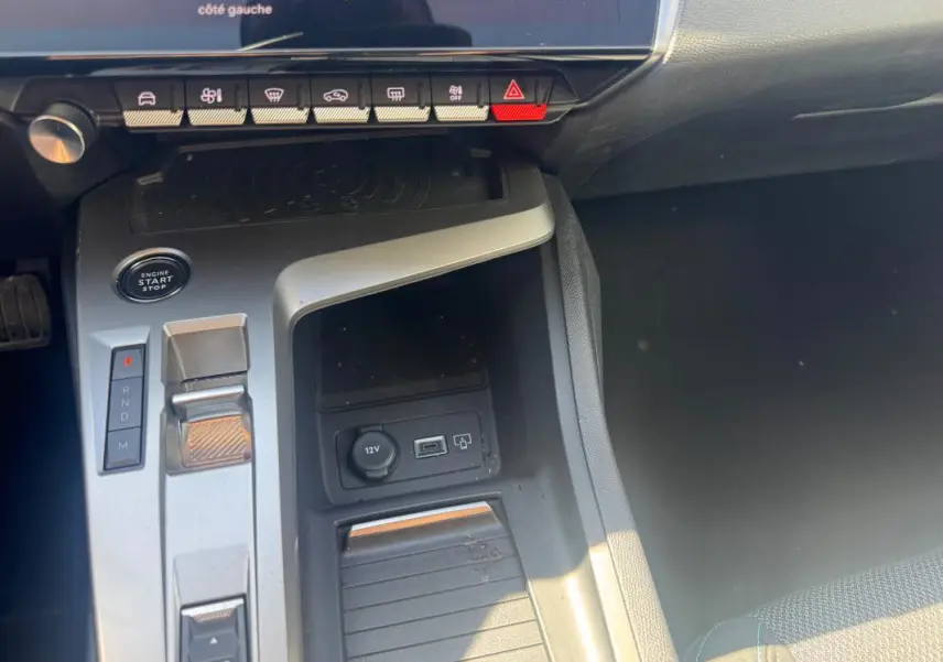 Vue rapprochée de la console centrale grise de la Peugeot 308 Hybrid 2025 avec levier de vitesse automatique et boutons de commande.