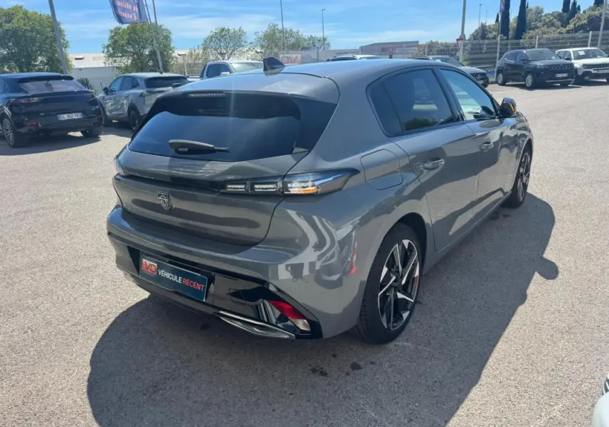 Vue 3/4 arrière droite d'une Peugeot 308 Hybrid gris métallisé avec jantes alliage 17 pouces sur parking.