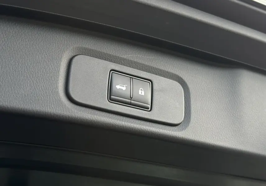 Gros plan sur les boutons de hayon électrique et verrouillage dans le coffre d'un Nissan Qashqai noir nacré.