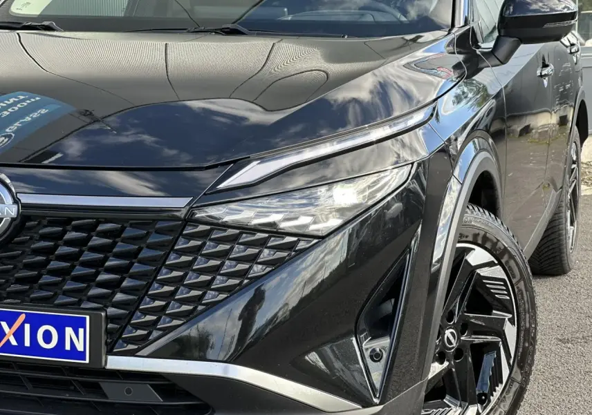 Vue avant droite rapprochée du Nissan Qashqai noir nacré avec calandre distinctive et jantes alliage 18 pouces.