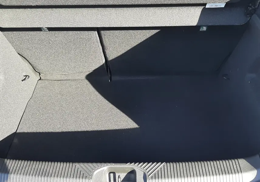 Coffre ouvert vu de dessus d’une Renault Clio VI TCE 115CH TECHNO gris Rafale, intérieur noir et tapis de sol.