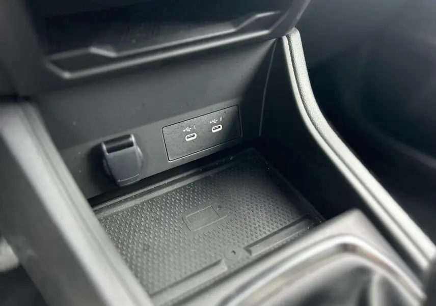 Gros plan sur la console centrale du Renault Captur 2025, montrant les ports USB et le chargeur sans fil noir.