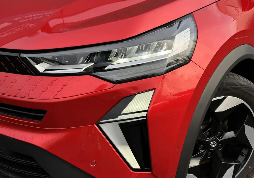 Gros plan sur l'avant droit du Renault Captur 2025 Rouge Flamme avec phares LED et jante alu noire diamantée.