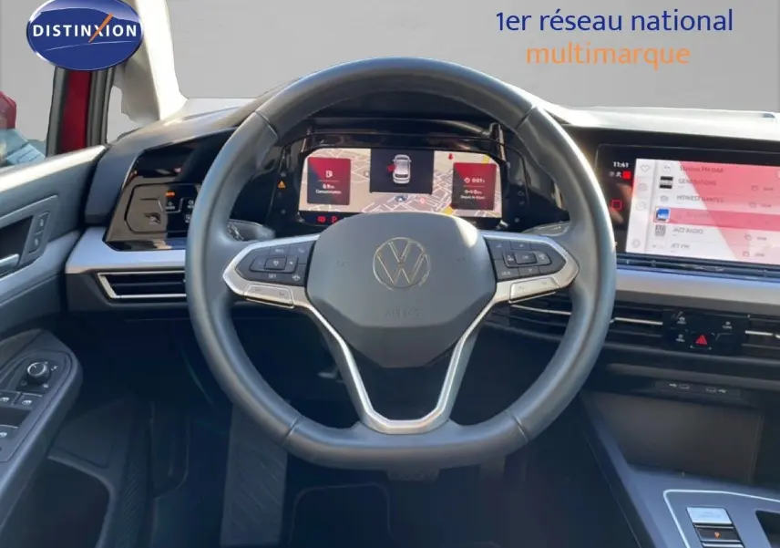 Vue intérieure centrée sur le volant et tableau de bord numérique d’une Volkswagen Golf VIII rouge Roi Metal de 2023.