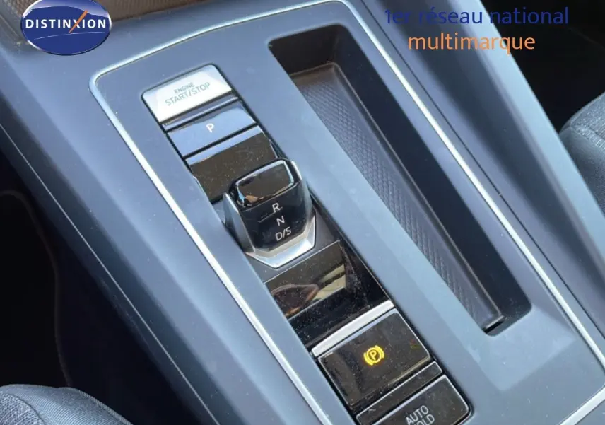 Gros plan sur la console centrale noire de la Volkswagen Golf VIII avec levier de vitesses automatique et bouton start/stop.