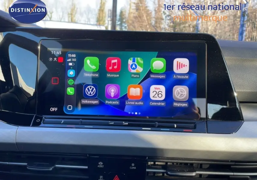 Vue intérieure centrée sur l'écran tactile multimédia de la Volkswagen Golf VIII rouge Roi Metal, affichant les applications connectées.