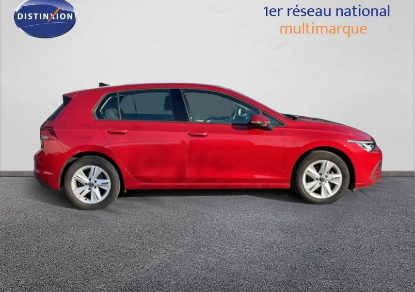 Profil droit d'une Volkswagen Golf VIII rouge roi métal, avec jantes alliage et vitres teintées, sur fond clair.