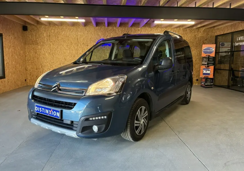 Citroën Berlingo Multispace bleu vue 3/4 avant droit en intérieur avec détails de calandre et phares allumés.