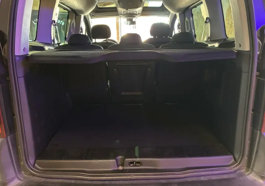 Vue arrière du coffre ouvert d’un Citroën Berlingo Multispace bleu, montrant l’espace de chargement et les appuie-têtes noirs des sièges arrière.