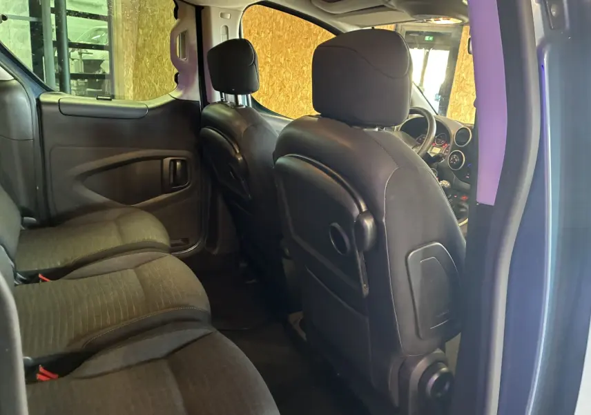 Vue intérieure côté gauche du Citroën Berlingo Multispace bleu, montrant les sièges arrière en tissu noir et le tableau de bord avant.