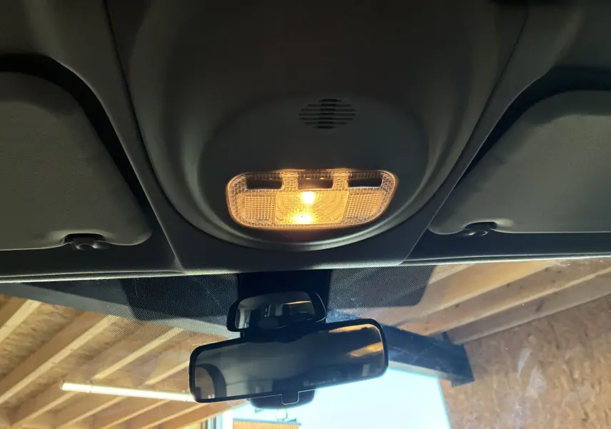 Vue intérieure centrée sur le plafonnier allumé et le rétroviseur intérieur d’un Citroën Berlingo Multispace bleu de 2017.