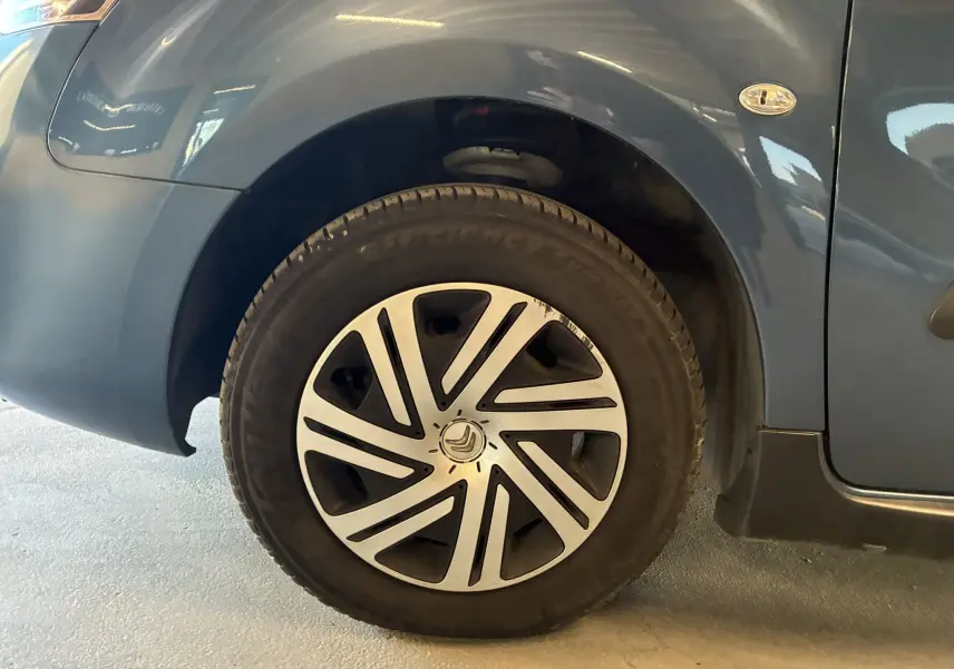Gros plan sur la roue avant gauche d’un Citroën Berlingo Multispace bleu avec jante en alliage au design moderne.