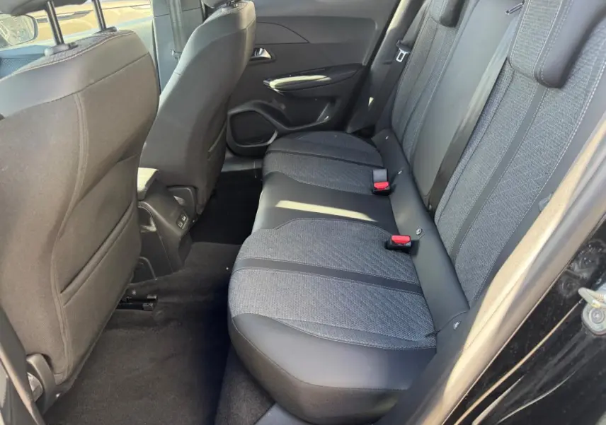 Vue côté droit de la banquette arrière noire et grise du Peugeot 2008 Hybrid 136 e-DCS6 Allure 2025 avec ceintures rouges.