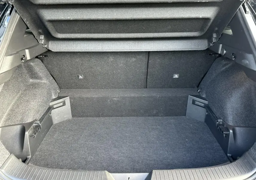 Coffre ouvert du Nissan Qashqai 2025 noir nacré, vue intérieure arrière montrant un plancher modulable et un hayon électrique.