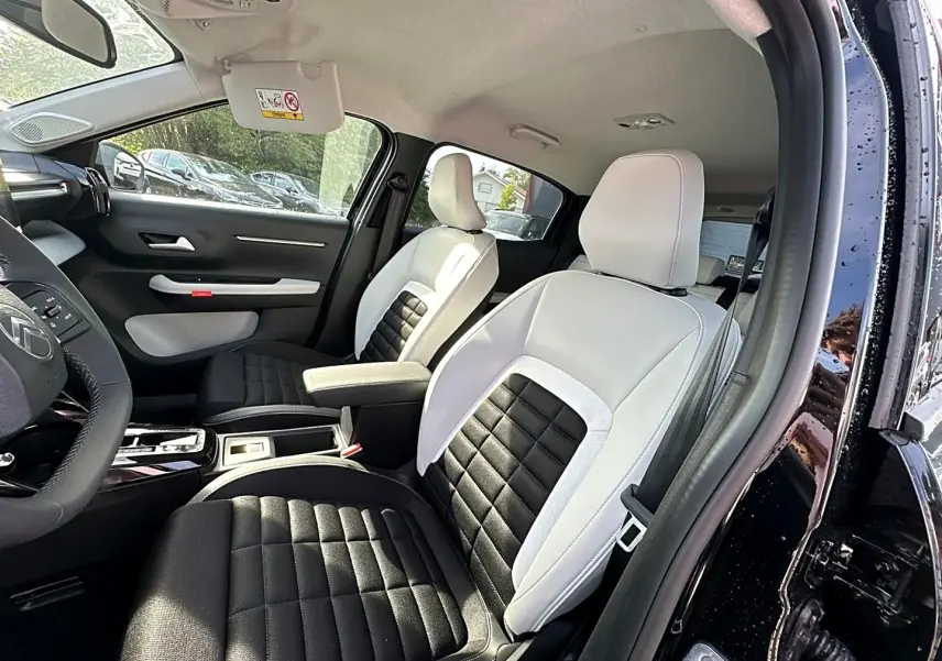 Vue intérieure côté conducteur du Citroën C3 Aircross noir 2026, sièges bicolores noir et blanc avec accoudoir central.