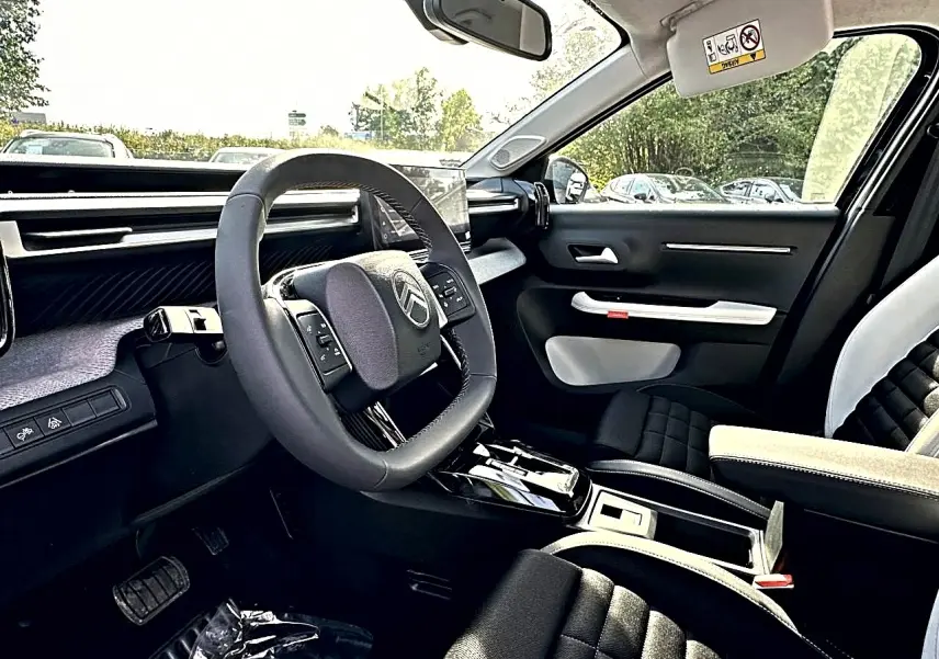 Vue intérieure côté conducteur du Citroën C3 Aircross 2026 noir, volant multifonction et sellerie noire avec accoudoir clair.