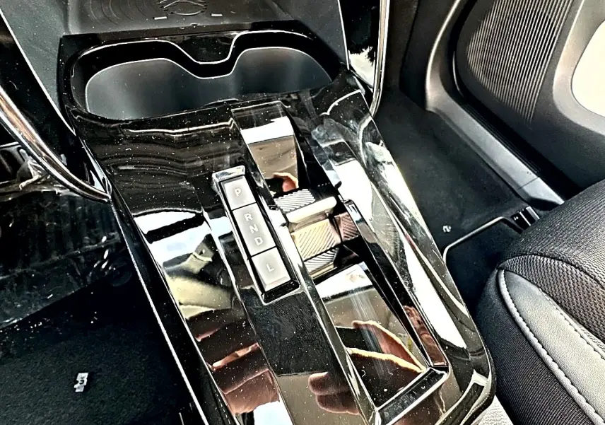 Gros plan sur la console centrale noire brillante avec levier de boîte automatique et porte-gobelets du Citroën C3 Aircross.