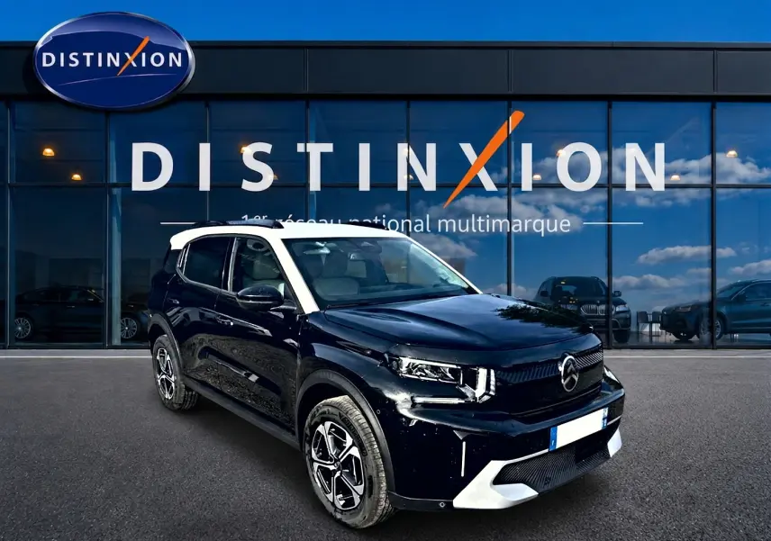 Citroën C3 Aircross noir avec toit blanc, vue 3/4 avant droite devant une vitrine Distinxion.
