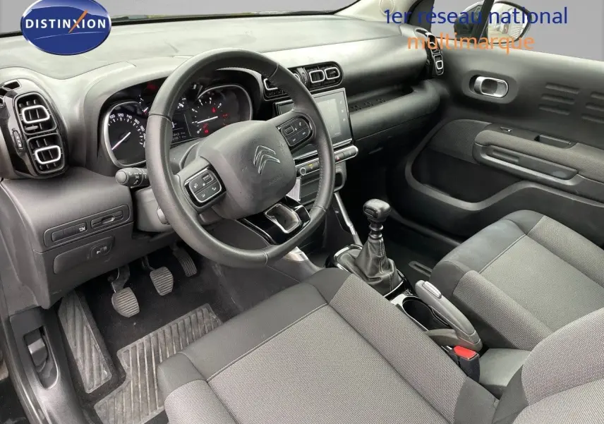 Intérieur du Citroën C3 Aircross 2023 en tissu gris, vue côté conducteur avec volant multifonction et boîte manuelle.