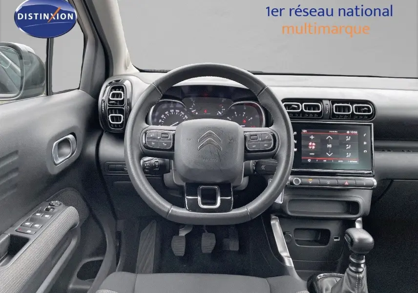 Vue intérieure centrée sur le tableau de bord et le volant d'une Citroën C3 Aircross 2023 noir perle métal avec boîte manuelle.