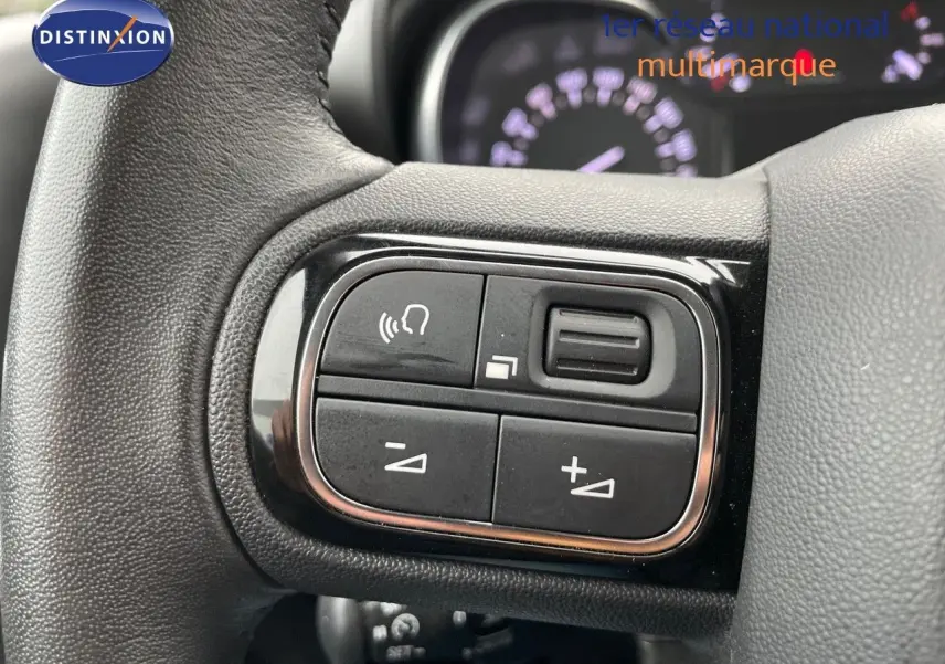 Gros plan sur les commandes du volant d'une Citroën C3 Aircross 2023 noir perle métal, version diesel Shine.