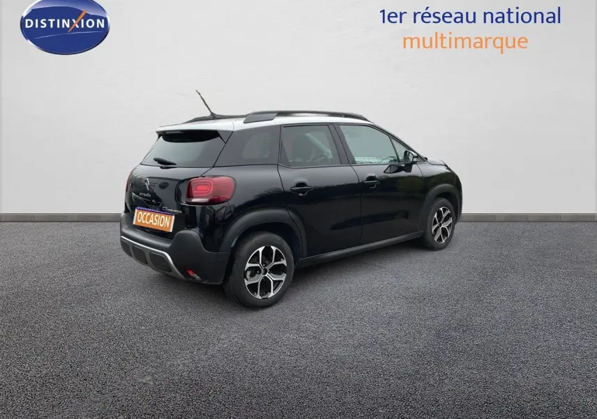 Vue 3/4 arrière droite d'une Citroën C3 Aircross noire perle métal avec jantes biton et toit blanc.