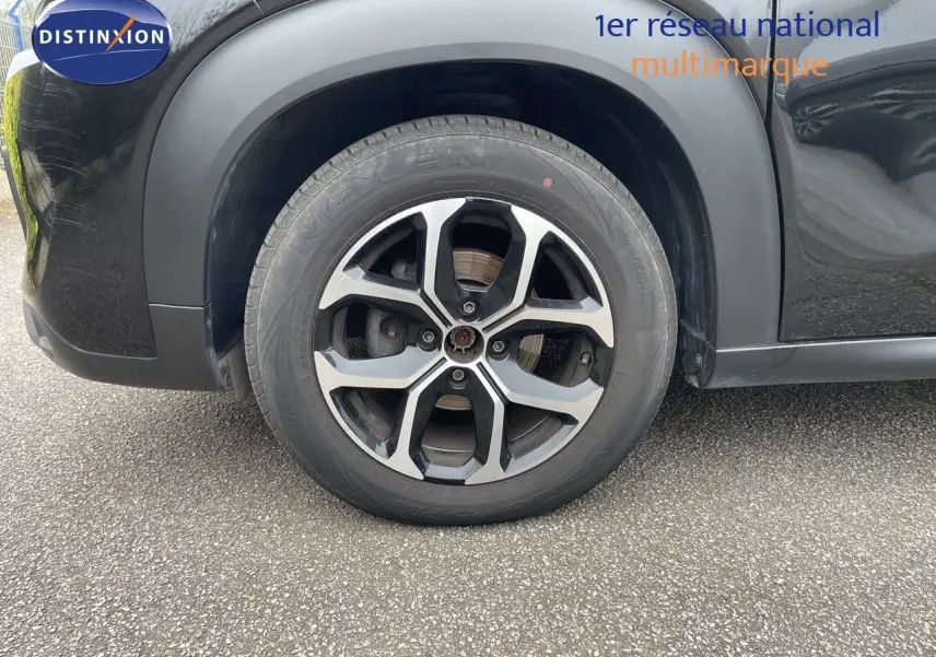 Gros plan sur la roue avant gauche noire perle métal d'une Citroën C3 Aircross 2023 avec jante alliage bicolore.