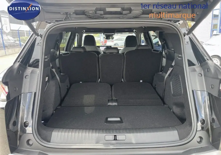 Coffre ouvert d'un Peugeot 5008 noir métal 2025, montrant les sièges arrière rabattus et l'espace de chargement spacieux.