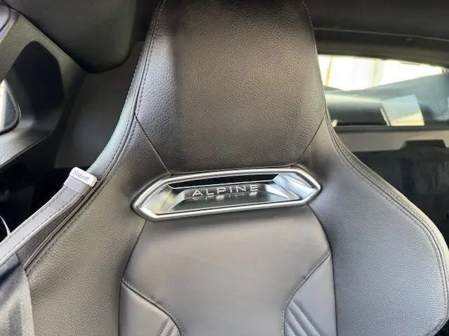 Vue intérieure côté gauche de la porte en cuir noir avec surpiqûres et poignée métallique de l'Alpine A110 Gris Acier Heritage 2021.