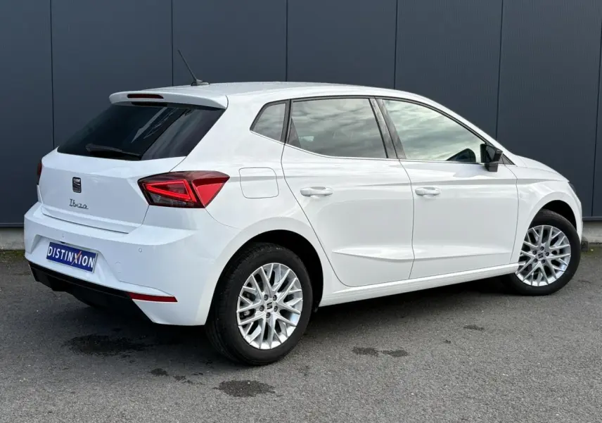 Vue 3/4 arrière droite d'une SEAT Ibiza blanche avec jantes alliage et vitres arrière surteintées.