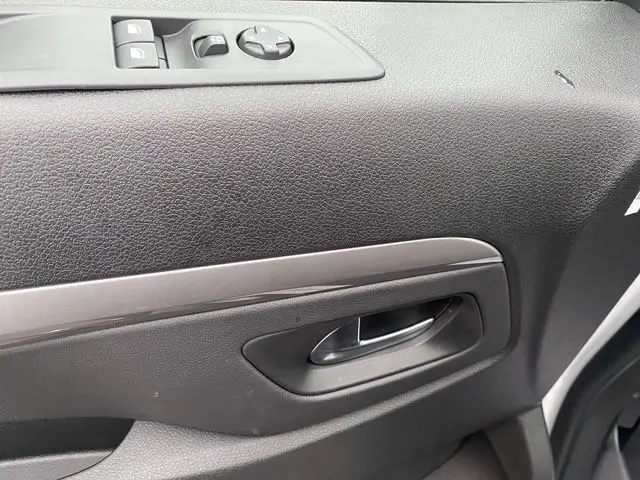 Gros plan sur la poignée intérieure et les commandes de lève-vitres côté gauche d'une porte noire du Citroën Jumpy XL blanc.