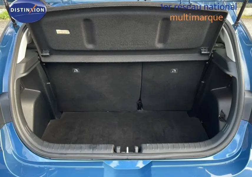 Coffre ouvert vu de l'arrière d'une Hyundai i20 1.0 TGDI 100CH KLASS bleu vibrant metal, intérieur noir et tapis de sol.