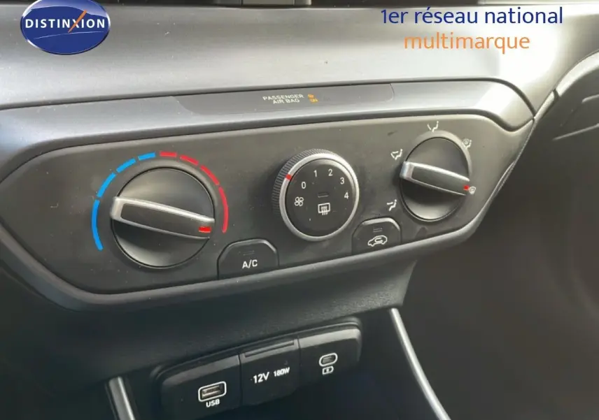 Gros plan sur la commande de climatisation et les ports USB d’une Hyundai i20 2025 en intérieur noir.