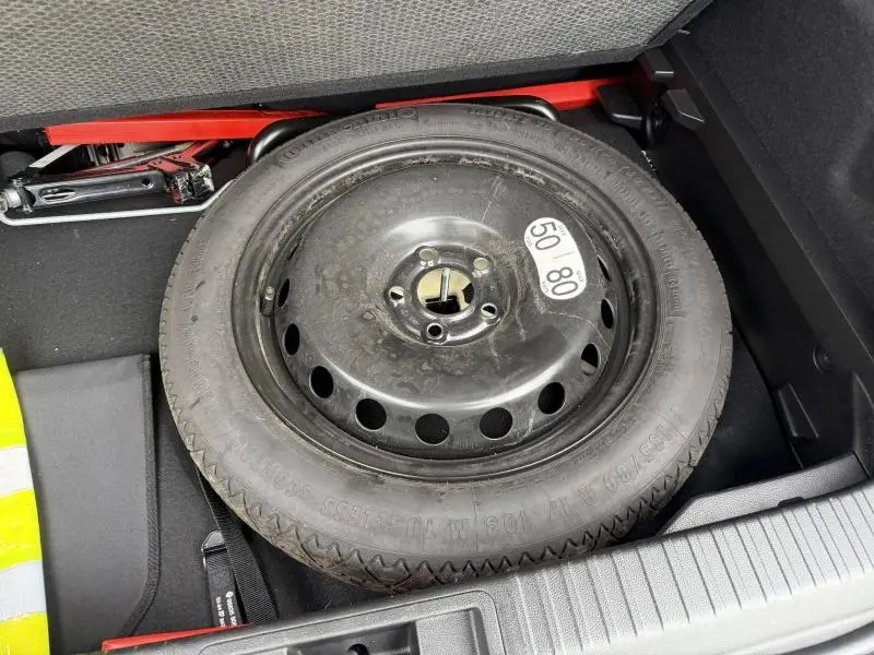 Vue rapprochée de la roue de secours noire dans le coffre du Renault Captur 1.6 E-Tech hybride 2025 Bleu Iron/Noir Etoilé.