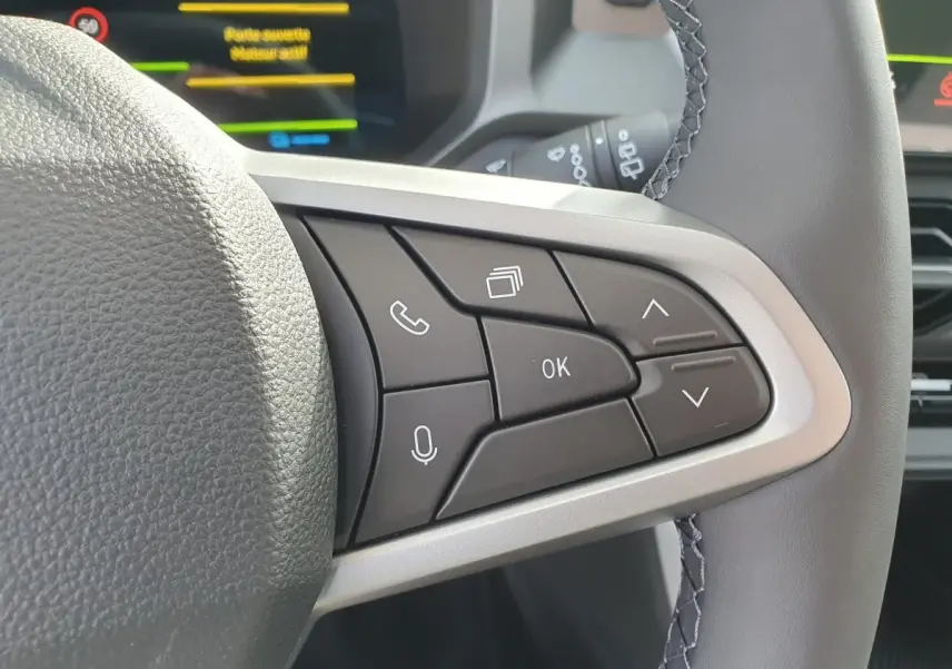 Gros plan sur les commandes multifonctions à droite du volant du Dacia Bigster, intérieur gris clair.