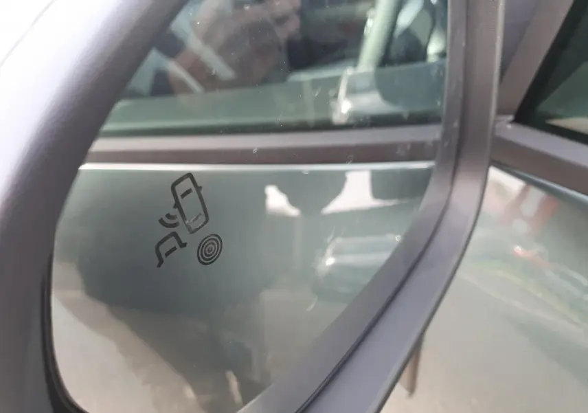 Gros plan sur le rétroviseur droit vert cèdre du Dacia Bigster 2026 avec icône d'alerte d'angle mort visible.