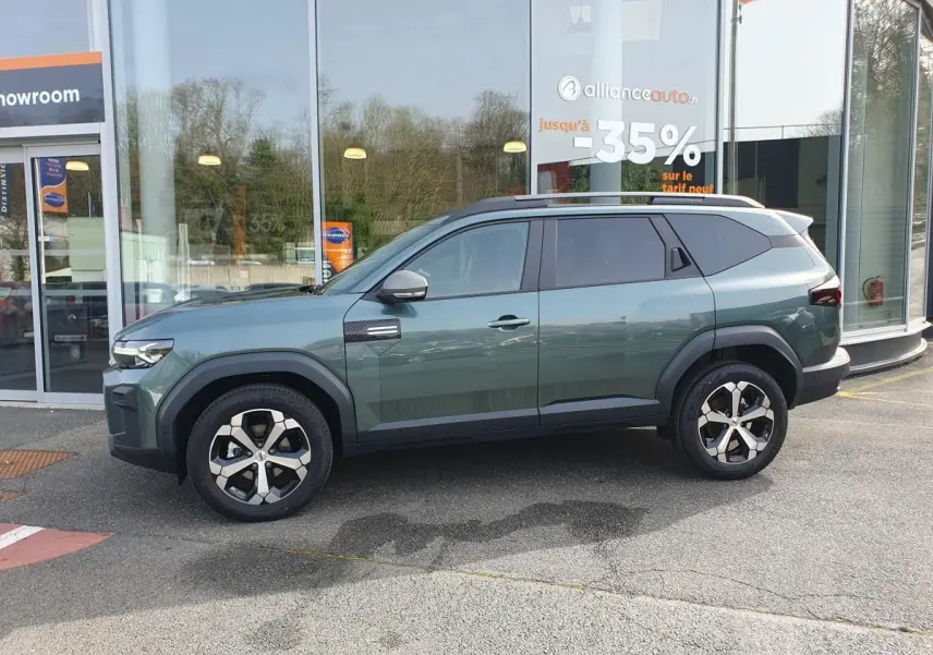 Vue de profil côté gauche du SUV Dacia Bigster vert cèdre avec jantes alliage 18” et toit panoramique visible.