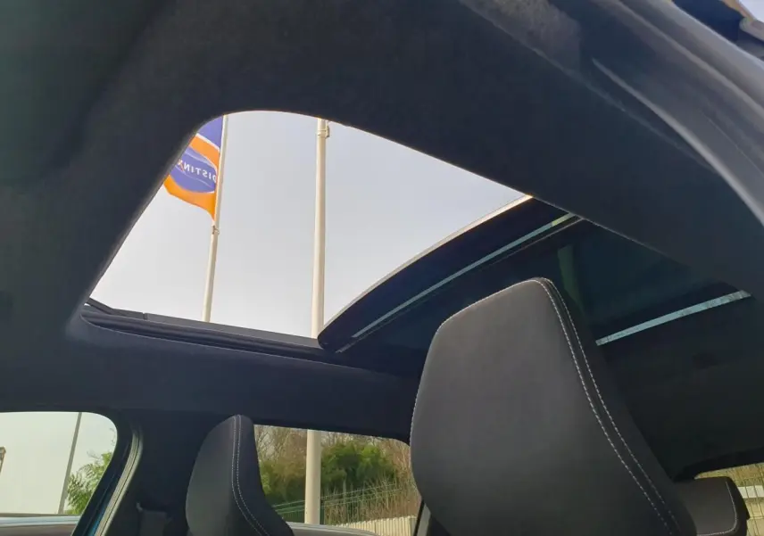 Vue intérieure du toit panoramique ouvert du Dacia Bigster 2026, avec appuie-tête avant en tissu noir.