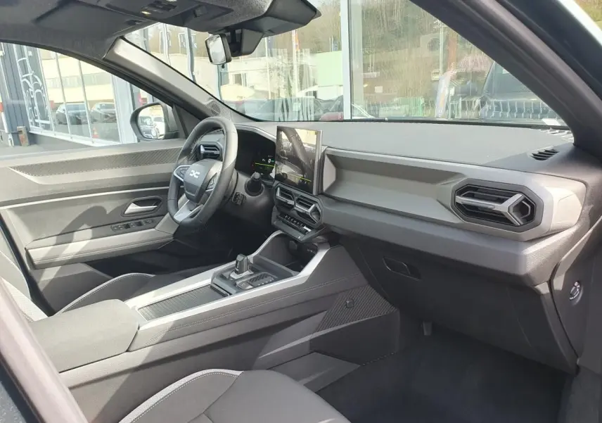 Intérieur du Dacia Bigster 2026 vu côté conducteur, tableau de bord moderne avec écran tactile vertical et volant multifonction.