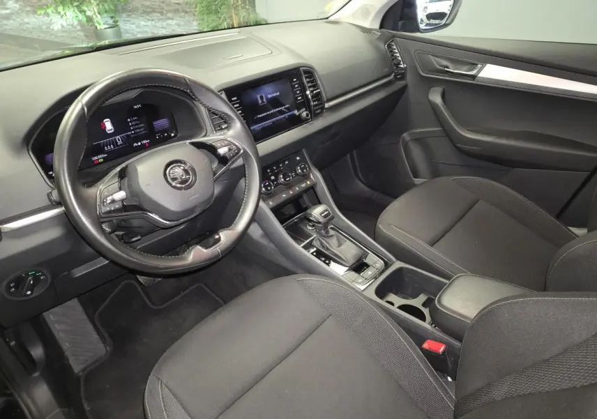 Vue intérieure avant droite du Skoda Karoq 2023 noir, avec volant cuir, tableau de bord digital et console centrale moderne.