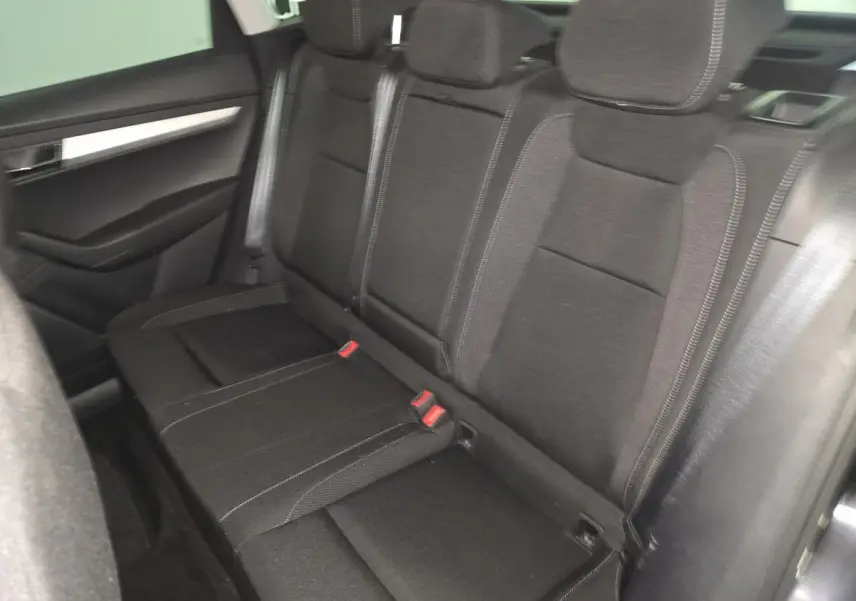 Vue intérieure du siège arrière côté droit en tissu noir du Skoda Karoq 2023 avec appuie-têtes et ceintures visibles.