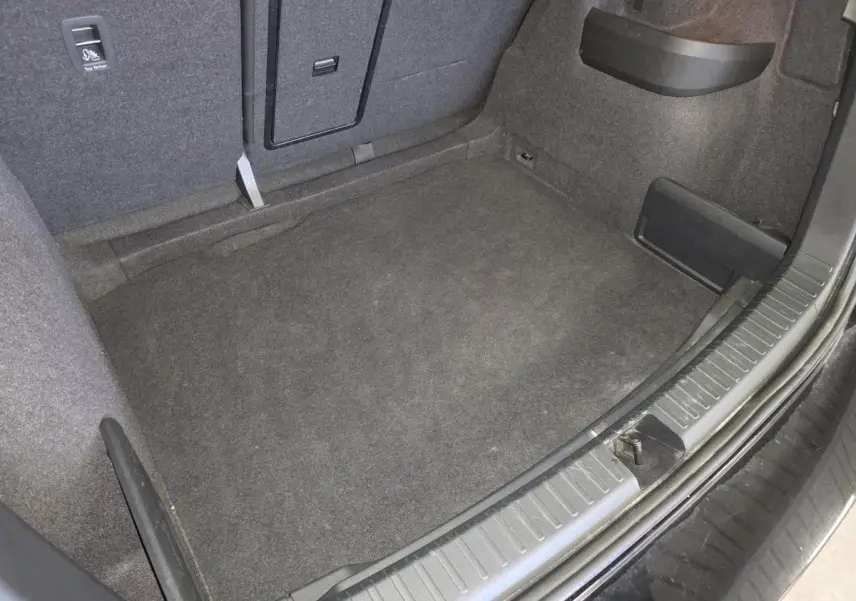 Coffre spacieux vu de dessus du Skoda Karoq noir 2023, avec tapis de sol gris et habillage intérieur sombre.