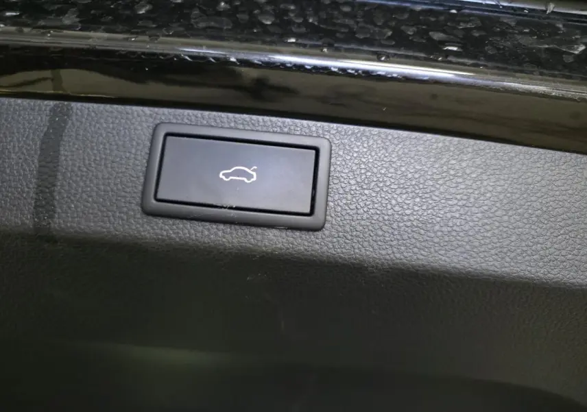 Bouton noir d'ouverture électrique du hayon sur la garniture intérieure d'un Skoda Karoq noir.