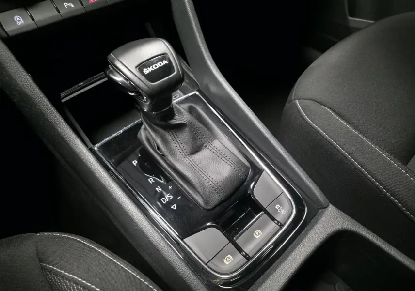 Gros plan sur le levier de vitesse automatique noir ŠKODA KAROQ 2023 avec coutures apparentes et commandes autour.